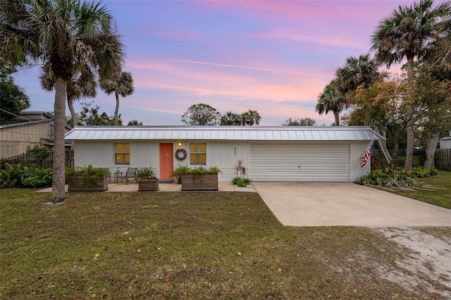 ranch-style home featuring a garage and a lawn