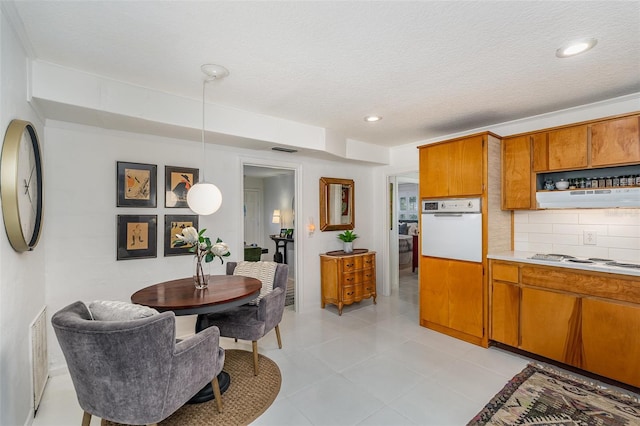 kitchen featuring light tile patterned flooring, tasteful backsplash, hanging light fixtures, white appliances, and a textured ceiling