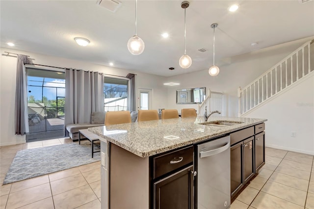 kitchen with light tile patterned flooring, sink, decorative light fixtures, a center island with sink, and dishwasher