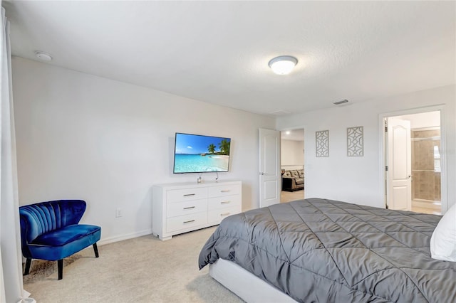 carpeted bedroom featuring ensuite bathroom and a textured ceiling