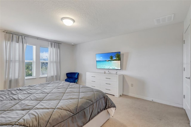 bedroom featuring light colored carpet and a textured ceiling