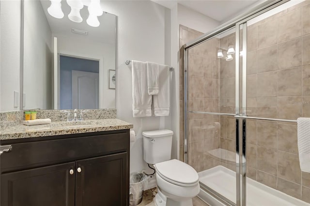 bathroom featuring vanity, a shower with shower door, and toilet