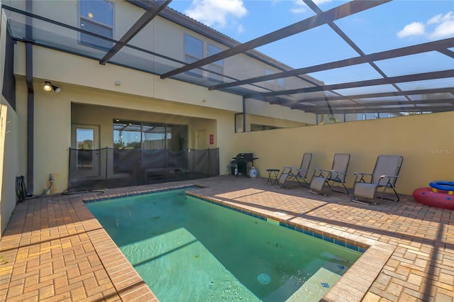 view of pool with a patio area and glass enclosure