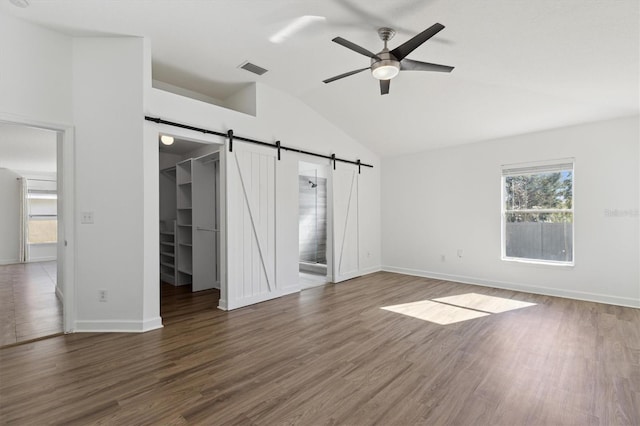 interior space featuring vaulted ceiling, a barn door, ceiling fan, and dark hardwood / wood-style flooring