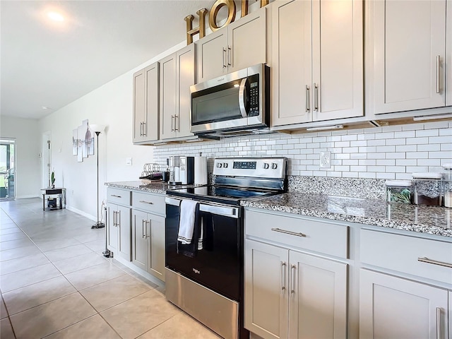 kitchen featuring light stone countertops, light tile patterned flooring, appliances with stainless steel finishes, and decorative backsplash