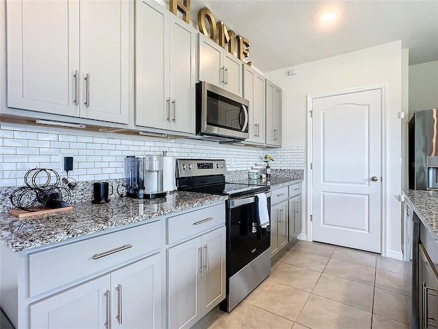 kitchen featuring stone counters, appliances with stainless steel finishes, light tile patterned floors, and decorative backsplash