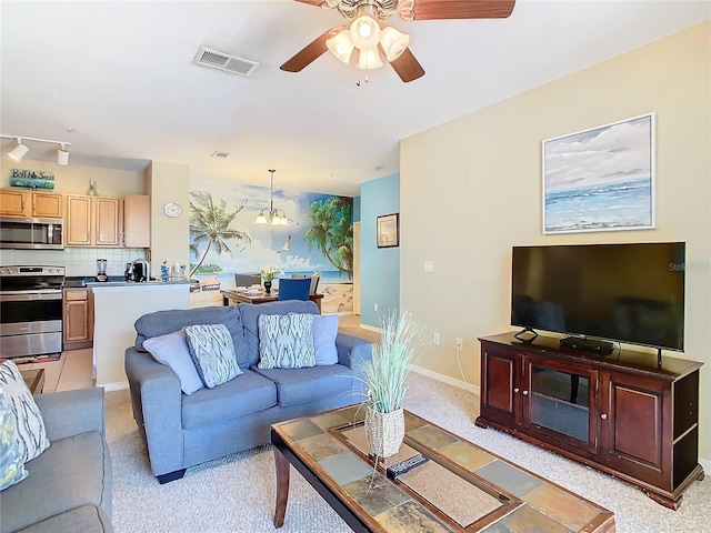 living room with ceiling fan with notable chandelier and track lighting