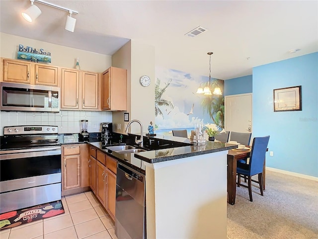 kitchen with stainless steel appliances, decorative light fixtures, sink, and kitchen peninsula