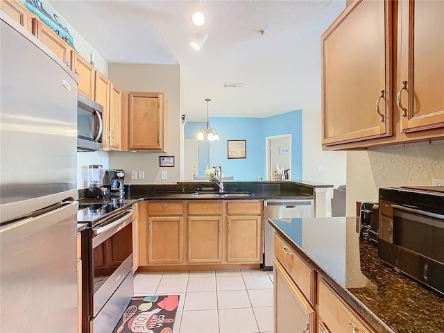 kitchen with sink, hanging light fixtures, dark stone counters, light tile patterned floors, and stainless steel appliances