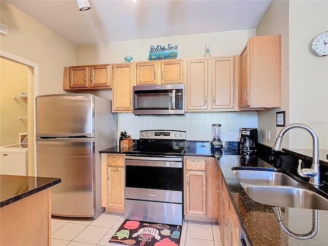 kitchen featuring stainless steel appliances, light tile patterned flooring, sink, and dark stone counters