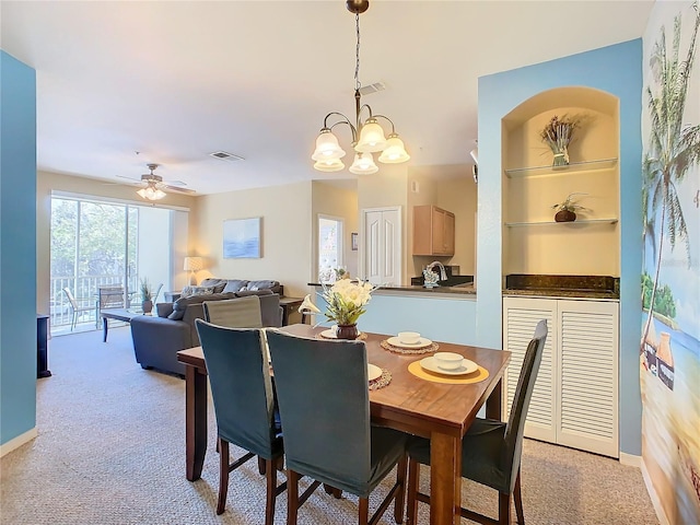 carpeted dining space featuring ceiling fan with notable chandelier