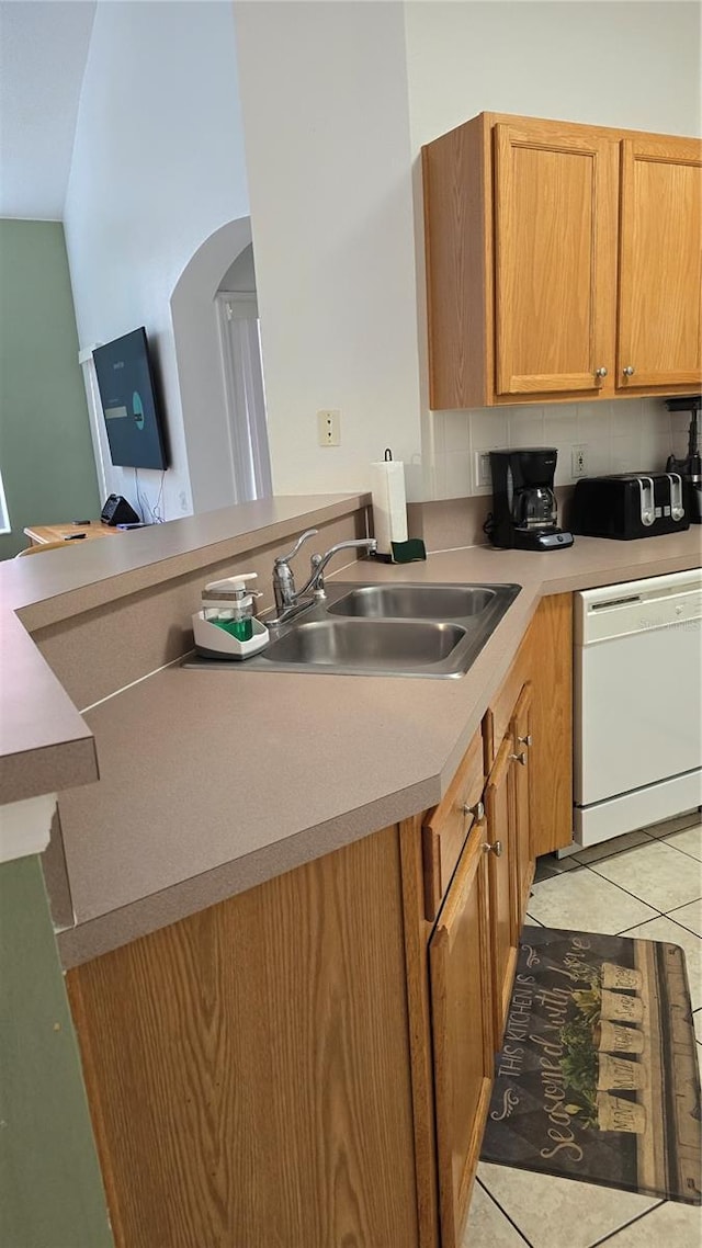 kitchen featuring white dishwasher, sink, light tile patterned floors, and backsplash