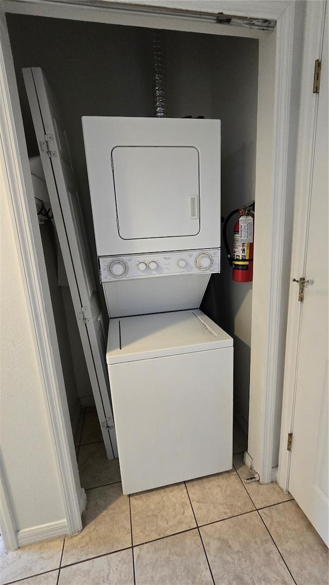 washroom with light tile patterned floors and stacked washing maching and dryer