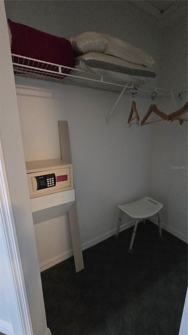 walk in closet featuring dark colored carpet