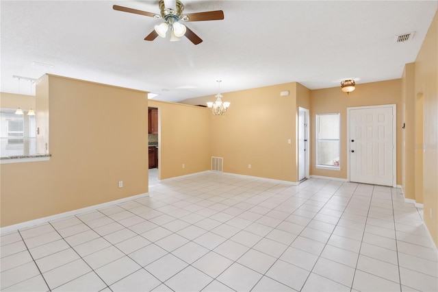 tiled empty room featuring ceiling fan with notable chandelier