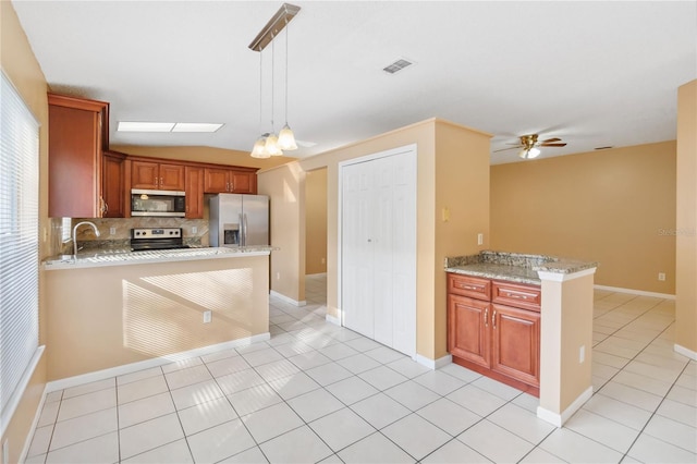 kitchen with pendant lighting, appliances with stainless steel finishes, backsplash, light stone counters, and light tile patterned flooring