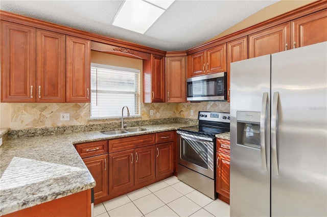 kitchen with light tile patterned flooring, appliances with stainless steel finishes, sink, backsplash, and light stone counters