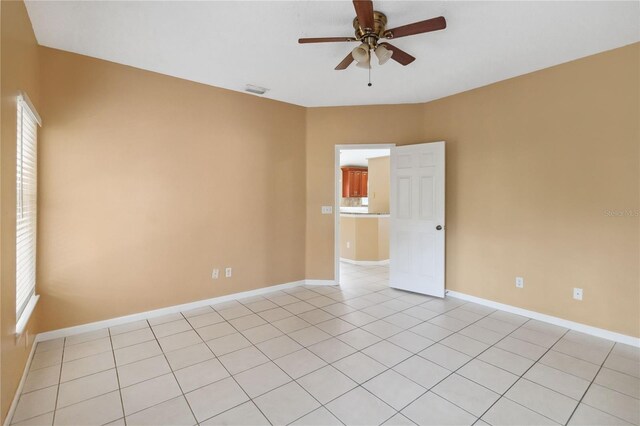 tiled empty room featuring ceiling fan