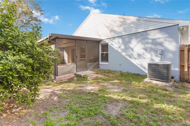 rear view of property featuring a sunroom and central AC unit