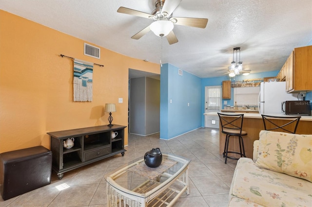 tiled living room featuring ceiling fan and a textured ceiling