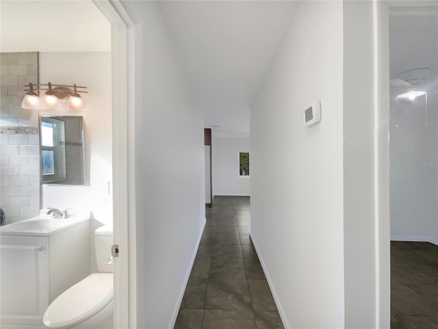 hallway featuring sink, plenty of natural light, and dark tile patterned floors