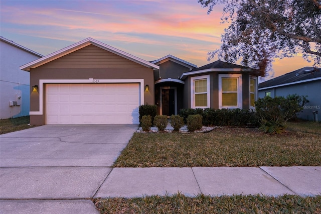 single story home with a garage and a lawn