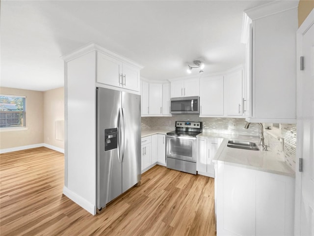 kitchen featuring sink, backsplash, stainless steel appliances, light hardwood / wood-style floors, and white cabinets