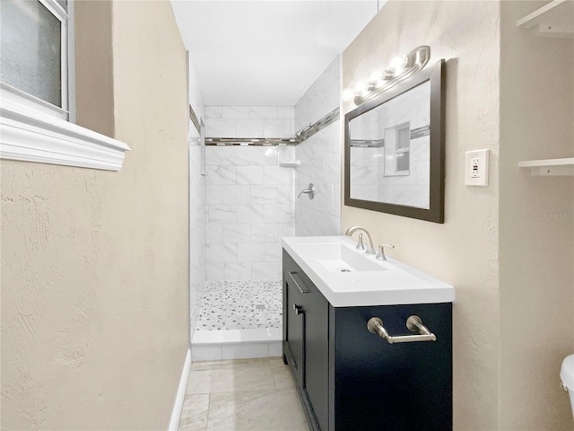 bathroom with a tile shower and vanity