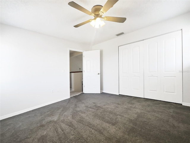 unfurnished bedroom with dark colored carpet, ceiling fan, and a closet