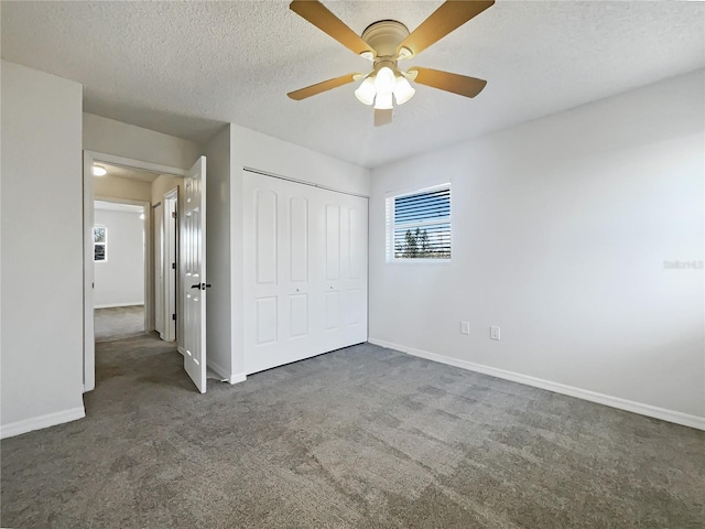 unfurnished bedroom featuring ceiling fan, dark carpet, a closet, and a textured ceiling