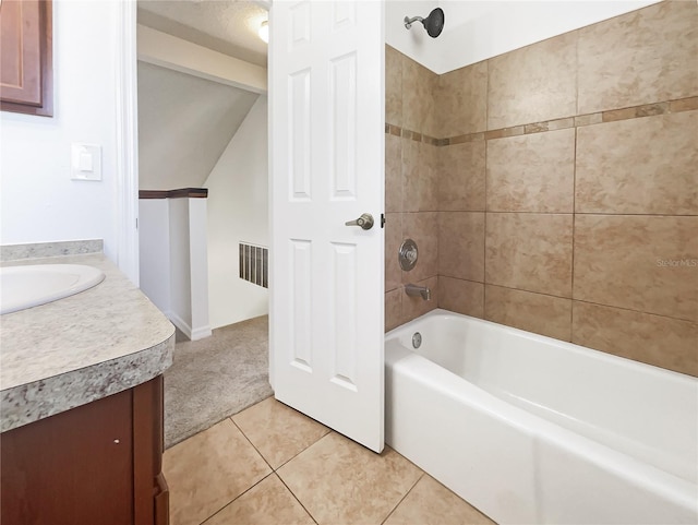 bathroom featuring vanity, tiled shower / bath combo, vaulted ceiling, and tile patterned floors