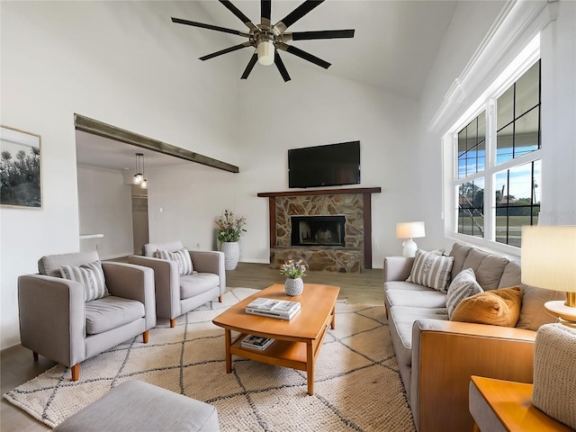 living room featuring ceiling fan, a fireplace, high vaulted ceiling, and light wood-type flooring