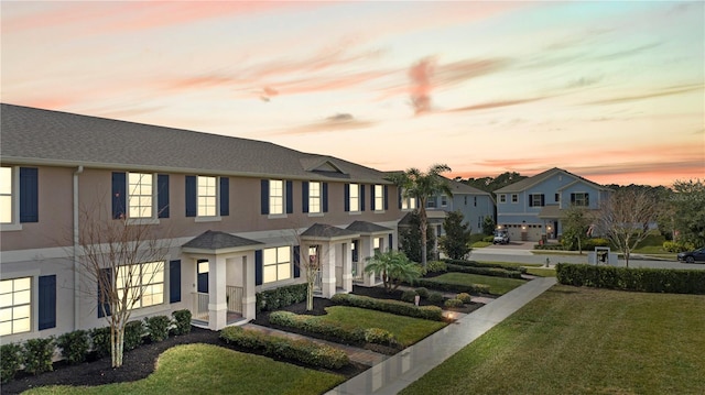 view of front of house featuring a residential view, a lawn, and stucco siding