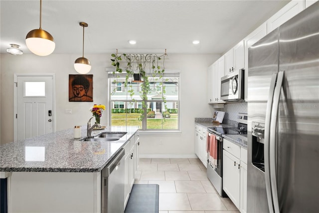 kitchen featuring sink, appliances with stainless steel finishes, white cabinetry, hanging light fixtures, and a kitchen island with sink