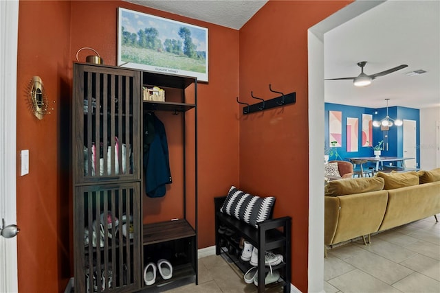 mudroom with ceiling fan with notable chandelier and light tile patterned floors