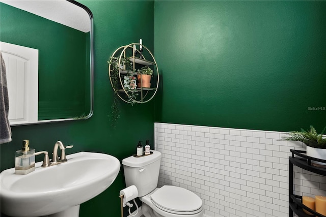 bathroom with toilet, a sink, and a textured wall