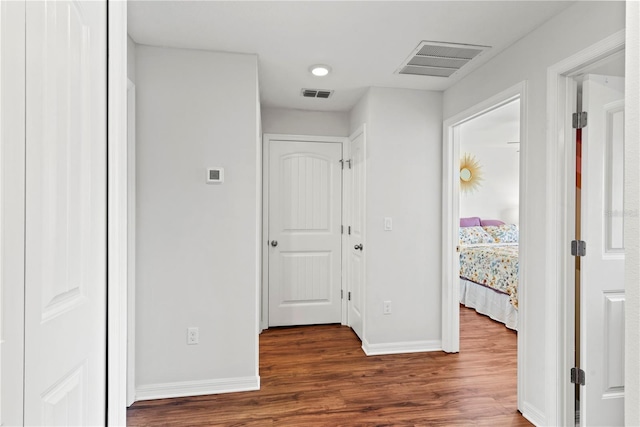 corridor featuring visible vents, baseboards, and wood finished floors