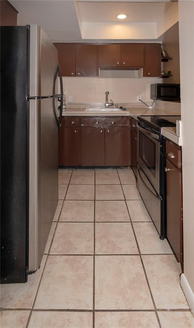 kitchen featuring stainless steel appliances, sink, dark brown cabinets, and light tile patterned floors