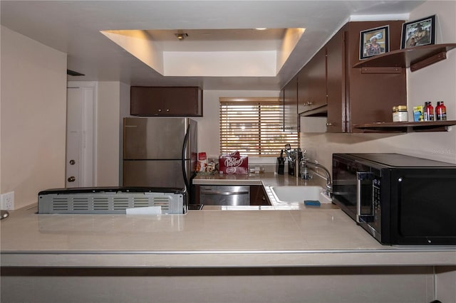 kitchen with appliances with stainless steel finishes, sink, dark brown cabinets, and a tray ceiling