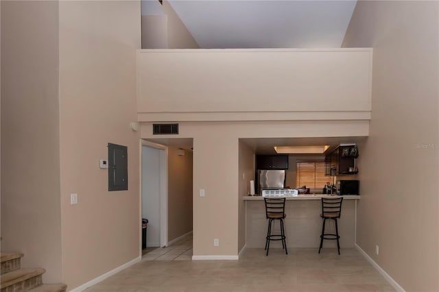 kitchen with fridge, electric panel, a breakfast bar, and light tile patterned floors