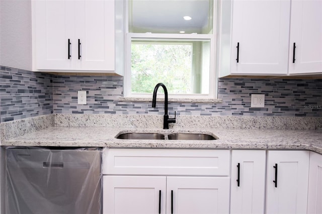 kitchen with white cabinetry, dishwasher, sink, and light stone counters