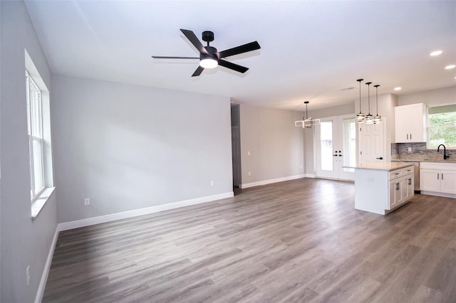 kitchen featuring a kitchen island, pendant lighting, white cabinets, backsplash, and hardwood / wood-style flooring