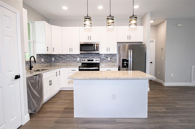 kitchen featuring a kitchen island, appliances with stainless steel finishes, sink, white cabinets, and hanging light fixtures