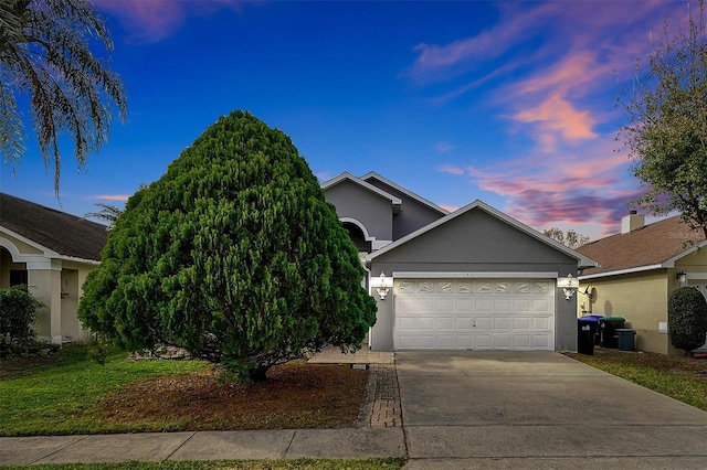 view of front of property featuring a garage, concrete driveway, and stucco siding