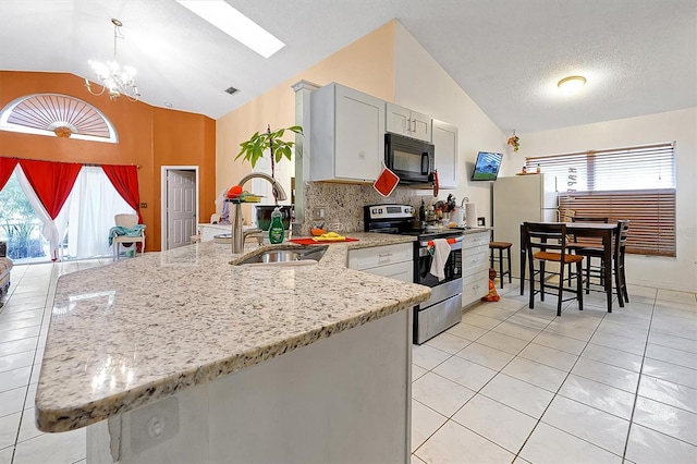 kitchen featuring sink, stainless steel electric range, hanging light fixtures, lofted ceiling with skylight, and white fridge