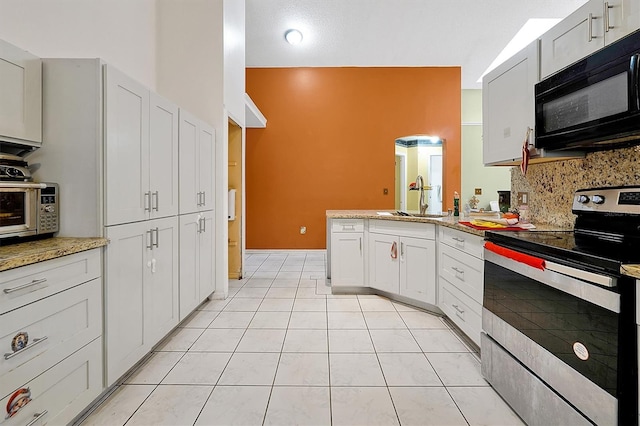 kitchen with decorative backsplash, white cabinets, electric stove, black microwave, and a sink