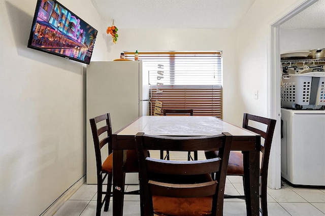 tiled dining space featuring washer / dryer and a textured ceiling