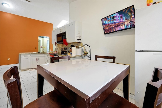 dining room featuring light tile patterned floors and vaulted ceiling