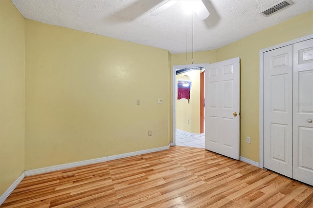 unfurnished bedroom with a closet, a textured ceiling, ceiling fan, and light hardwood / wood-style floors