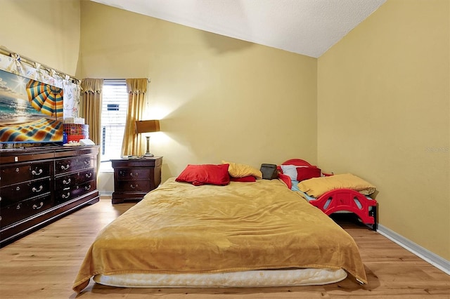 bedroom featuring light hardwood / wood-style floors and vaulted ceiling